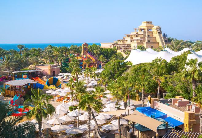 View of Aquaventure Water Park, Neptune tower and people playing in the pool